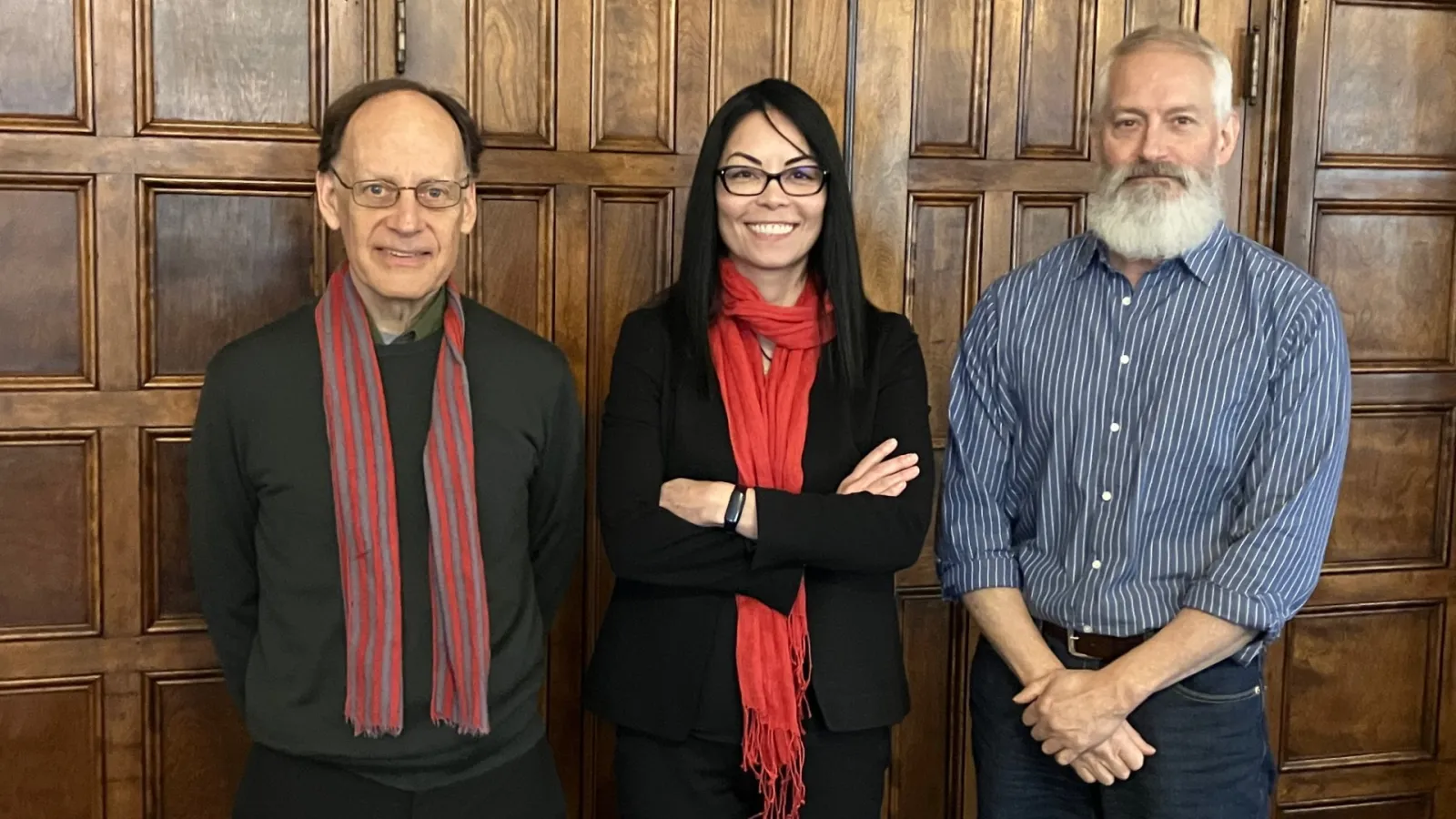 Three people standing in front of a wooden wall