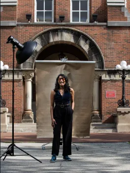 Sampada Aranke in front of University Hall, smiliing with a light and backdrop